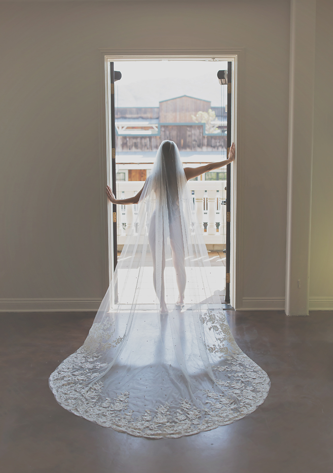 Bride with extra long veil standing in the door way in Temecula photographed by Kellie Foster with Spark Boudoir