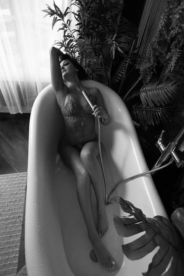 Black and White photo of a woman in a bathtub wearing lingerie.